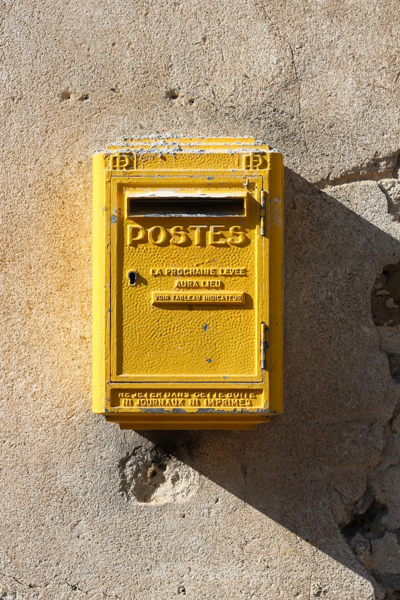 Photo by Brina Blum yellow steel mail box mounted on gray wall